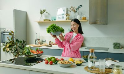 A Woman in Pink Long Sleeves Standing in the Kitchen while Holding a Bowl of Lettuce